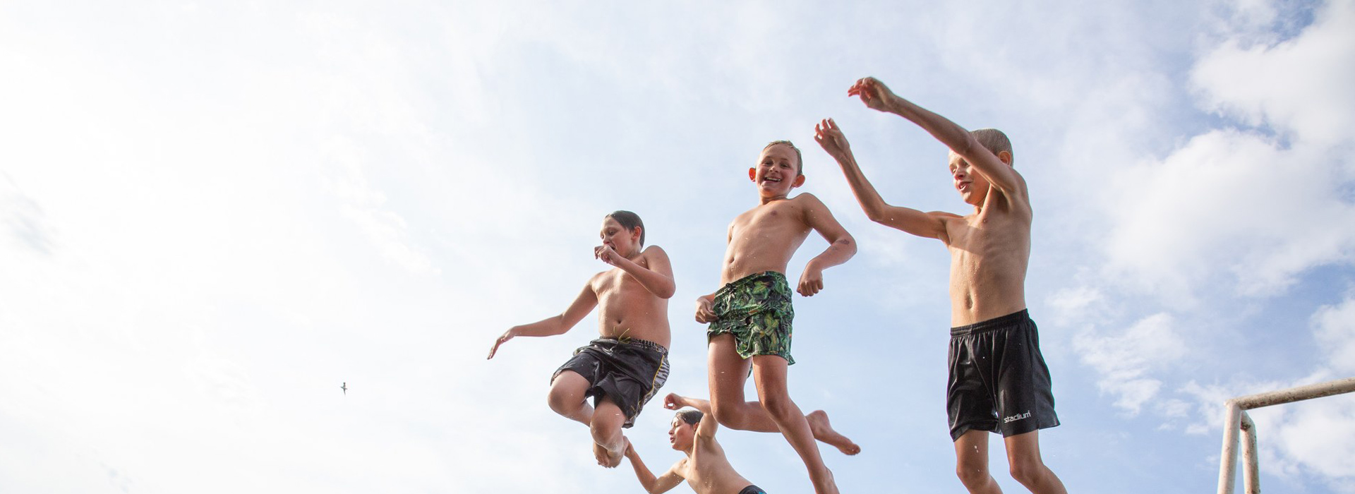 Lapset hyppäävät hyppytornista veteen.